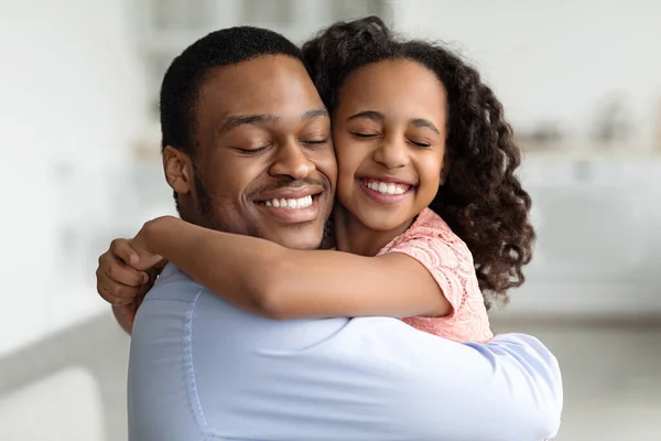 Padre negro extático e hija abrazándose con los ojos cerrados — Foto de Stock