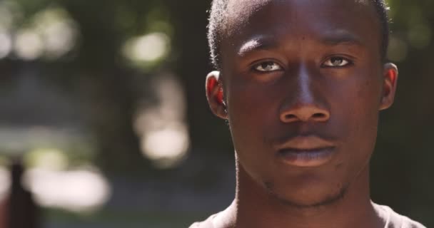 Ritratto ravvicinato di giovane ragazzo afroamericano serio che guarda rigorosamente la telecamera, posa all'aperto, rallentatore — Video Stock
