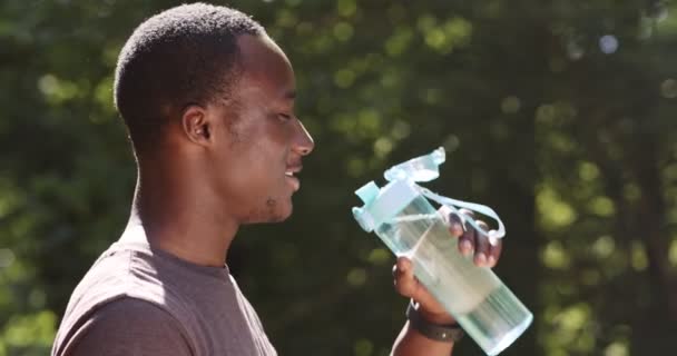 Sport e concetto di idratazione. Giovane afro-americano atleta acqua potabile, a riposo durante l'allenamento all'aria aperta — Video Stock