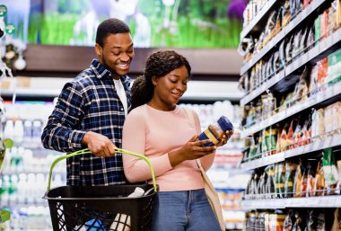 Genç Afro-Amerikalı çift market alışverişi yapıyor, süpermarkette iyi kahve seçiyorlar.
