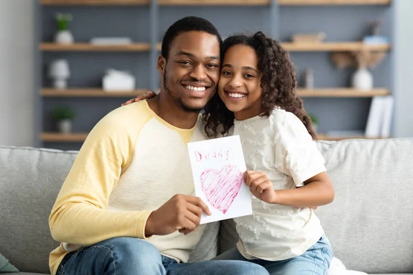 Cute black girl with gift card hugging her father — Stock Photo, Image