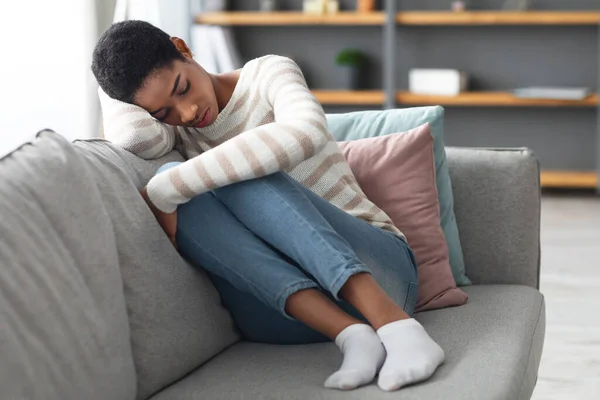 Concepto de Depresión. Retrato de la triste mujer africana sentada en el sofá en casa — Foto de Stock