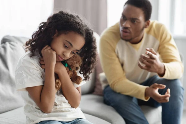 Furious black dad shouting at his frightened little daughter