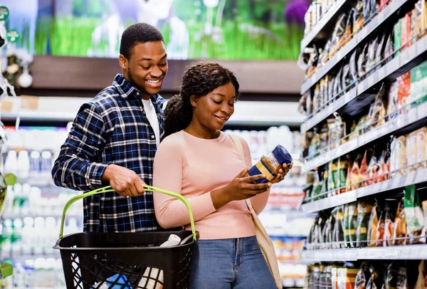 若いアフリカ系アメリカ人のカップルが食料品を買い、スーパーマーケットでおいしいコーヒーを選ぶ — ストック写真