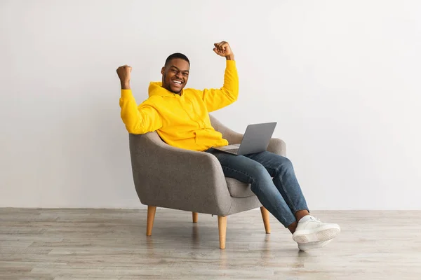 Chico con el gesto del ordenador portátil Sí Sentado en sillón, fondo gris —  Fotos de Stock