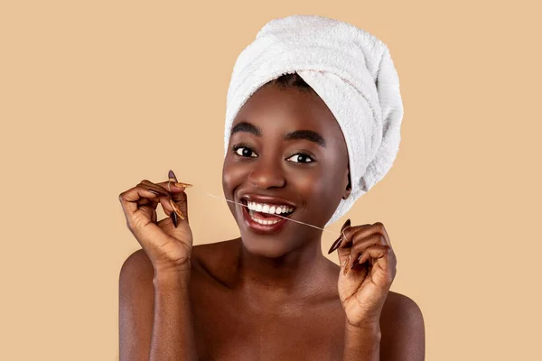 Молода чорна жінка використовує зубну нитку, дивлячись на камеру — стокове фото