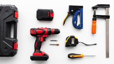 Beyaz arkaplandaki çeşitli enstrümanlar, üst görünüm. Alet çantası, elektrikli matkap, cetvel ve klemp araçları, düz konum