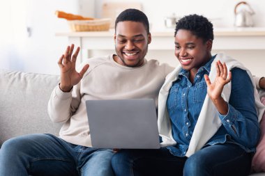 Siyah çift el sallayan dizüstü bilgisayarla video görüşmesi yapıyor.