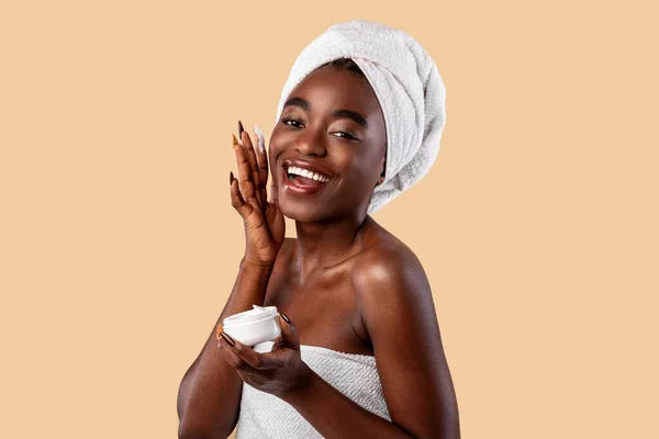 Bela jovem afro-americana aplicando creme facial de jar — Fotografia de Stock