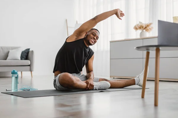 Χαρούμενος μαύρος κάνει πλευρική κάμψη τεντώνοντας την άσκηση στο σπίτι — Φωτογραφία Αρχείου