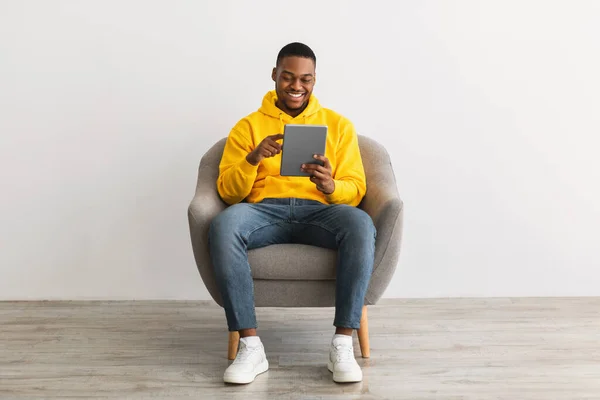 Chico negro feliz usando la tableta digital que navega Internet, fondo gris —  Fotos de Stock