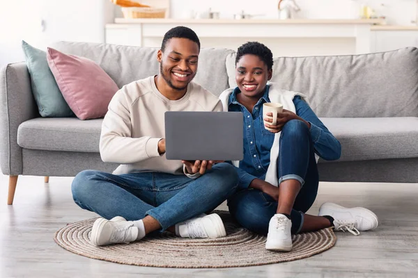 Pareja afroamericana sentada en el suelo, usando laptop —  Fotos de Stock