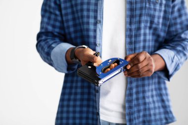 Tanımlanamayan siyah marangoz elinde inşaat zımbası, beyaz arka planda duruyor.