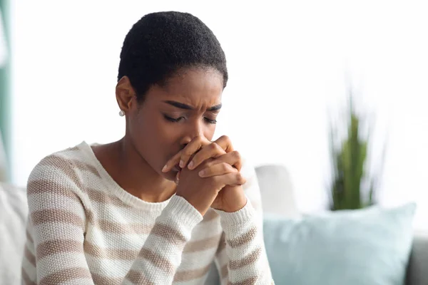 Konzept der Verzweiflung. Porträt einer depressiven Afrikanerin, die zu Hause auf der Couch sitzt — Stockfoto