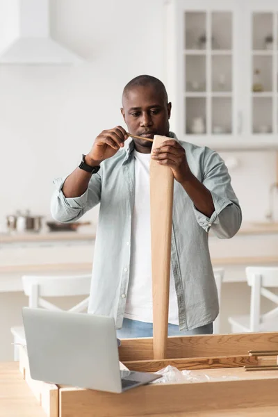 Modern tamirci ve online talimatlar. Siyah adam manuel tornavidayla mutfakta masa bacağına sikişiyor. — Stok fotoğraf
