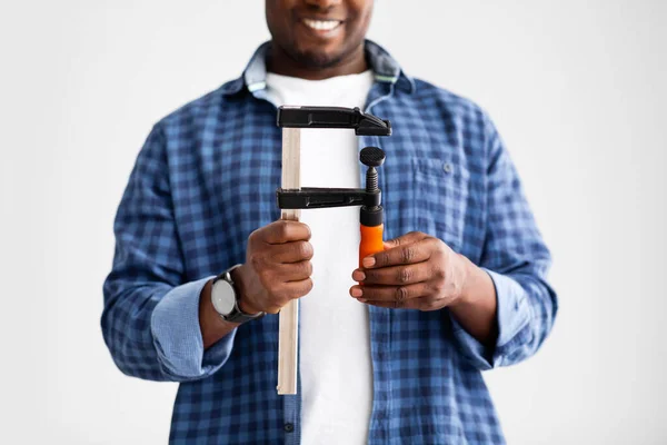 Zwarte mannelijke handen houden bouwgereedschap klem, klaar voor reparaties thuis, staan op witte muur studio achtergrond — Stockfoto