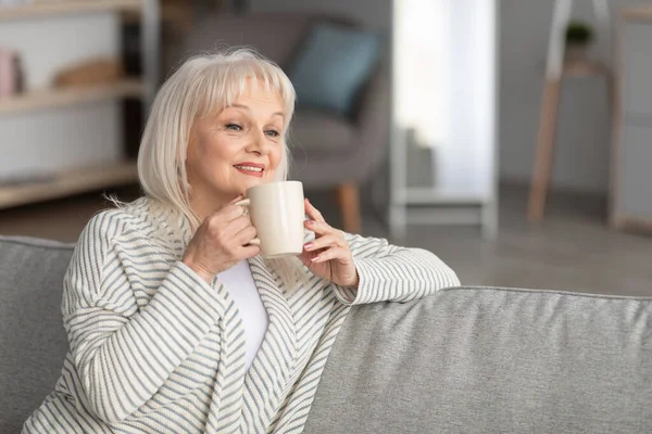 Портрет улыбающейся зрелой женщины, пьющей горячий кофе — стоковое фото