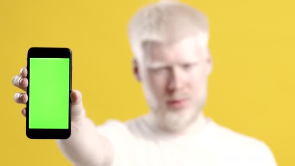 Albino Guy toont Smartphone met Chroma Key Screen, gele achtergrond — Stockvideo