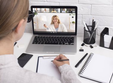 Genç bayan iş arkadaşlarıyla çevrimiçi iş görüşmesi yapıyor, öğretmeniyle ve bilgisayardaki öğrenci arkadaşlarıyla konuşuyor.