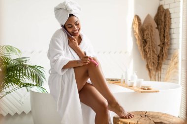 İçerde tıraş olurken telefonda konuşan neşeli Afrikalı kadın.