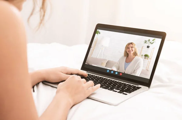 Jovem mulher videoconferência com sua mãe madura na webcam, usando laptop pc para falar com seu pai na cama — Fotografia de Stock