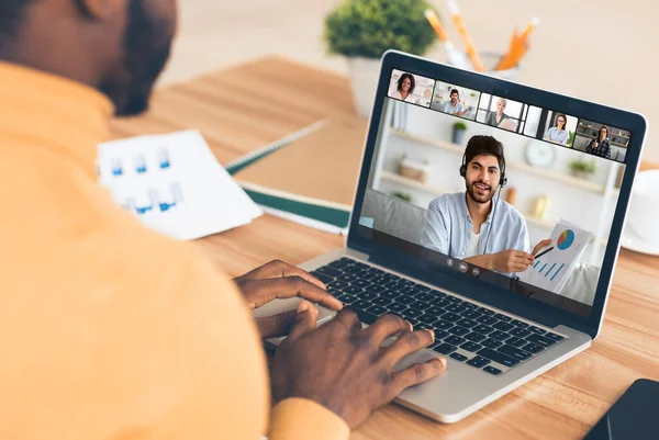 Afro-Américain ayant appel vidéo sur ordinateur portable avec un groupe de collègues d'affaires au bureau à domicile — Photo