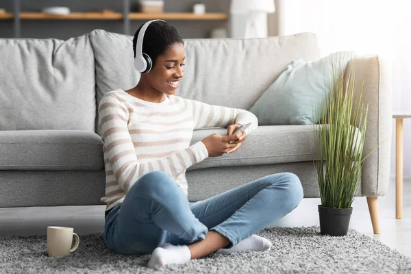 Lazer de fim de semana. Feliz Preto Feminino Ouvindo Música E Usando Smartphone Em Casa — Fotografia de Stock