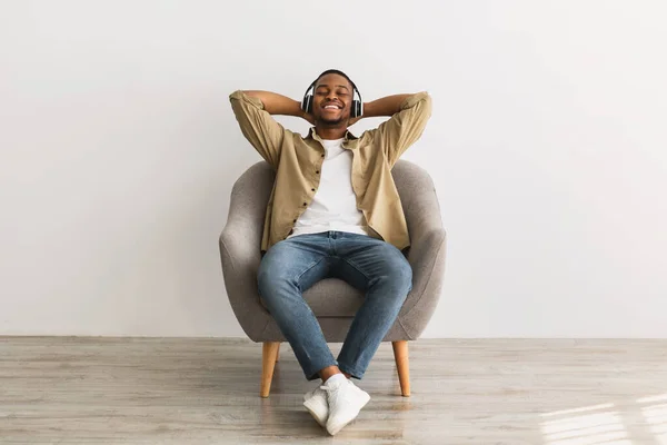 Hombre africano escuchando música usando auriculares sobre fondo gris —  Fotos de Stock