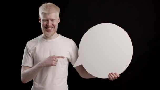 Alegre albino cara mostrando branco discurso bolha sobre preto fundo — Vídeo de Stock