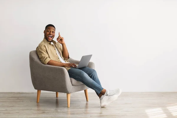 Negro chico con portátil tener idea sentado en silla interior —  Fotos de Stock