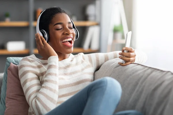 Tempo libero preferito. Black Lady che canta mentre ascolta musica su smartphone a casa — Foto Stock