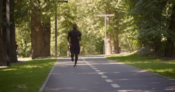Αθλητικά τραύματα. Νεαρός ενεργός Αφροαμερικάνος που τρέχει στο πάρκο, ψεκάζει το πόδι του, υποφέρει από οξύ πόνο στα πόδια. — Αρχείο Βίντεο