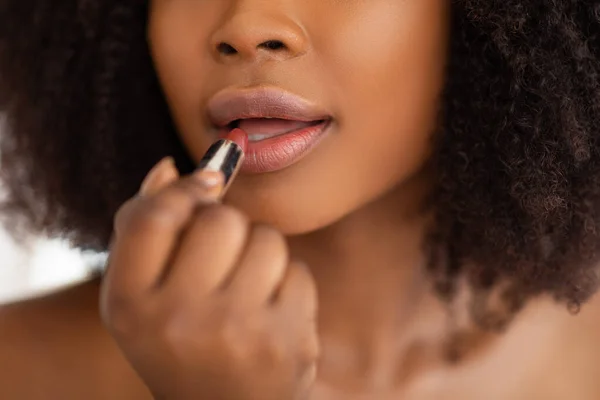 Pandangan terpotong dari wanita kulit hitam muda yang mengoleskan lipstik dari tabung, mengenakan riasan dekoratif, menutup — Stok Foto