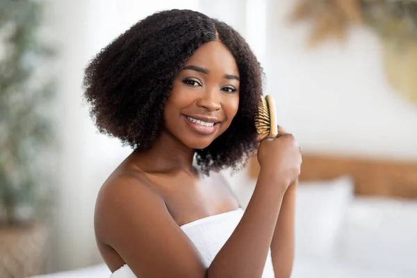 Portret van gelukkig jong zwart dame borstelen haar krullend donker haar thuis — Stockfoto
