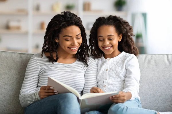 Радостная черная мать и дочь вместе читают книгу — стоковое фото