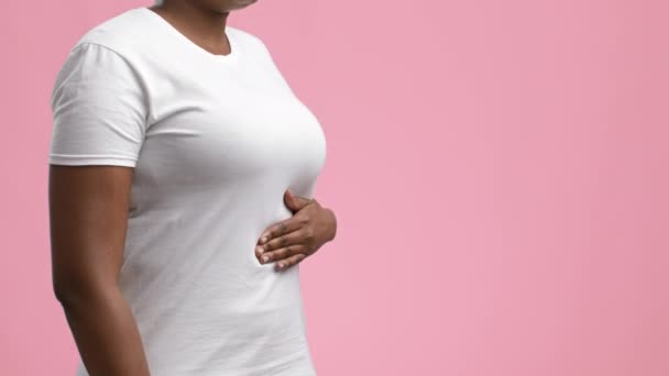 Irreconocible dama africana tocando el abdomen con dolor de estómago, fondo rosa — Vídeo de stock