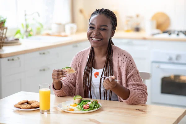 Alegre negro dama comer sabroso desayuno o almuerzo en cocina en casa — Foto de Stock