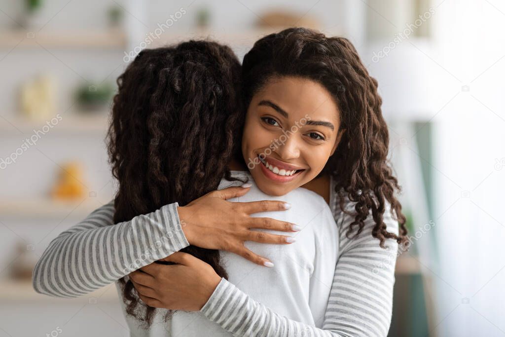 Positive black mother hugging her daughter, closeup