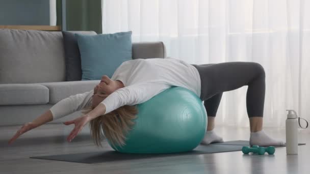 Äldre kvinna gör pilates Stretching motion ligger på Fitball inomhus — Stockvideo