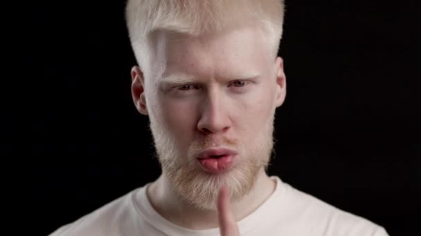Albino ragazzo gesturing dito su labbra posa su nero sfondo — Video Stock