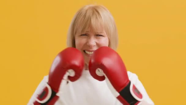 Força feminina. Irritada senhora sênior vestindo luvas de boxe espunching mãos em exílio, sentindo-se furioso — Vídeo de Stock