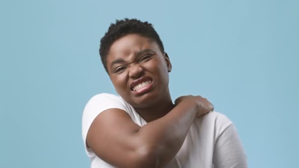 Unhappy Black Woman Massaging Aching Neck And Shoulders, Blue Background