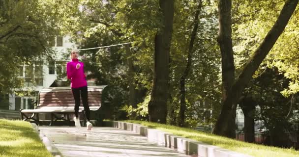 Prática desportiva na cidade. Jovem mulher ativa correndo no parque urbano vazio, desfrutando da manhã ativa sozinha — Vídeo de Stock