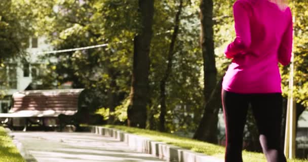 Morgens Joggingtraining. Rückenansicht einer jungen sportlichen blonden Frau, die allein im grünen Stadtpark läuft, Zeitlupe — Stockvideo