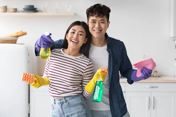 Gelukkig aziatische jonge man en vrouw met schoonmaak benodigdheden — Stockfoto