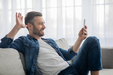 Mutlu adamın akıllı telefondan video konferansı yaparken yan görünümü