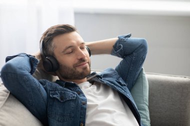 Müzik dinleyen orta yaşlı, neşeli bir adam.