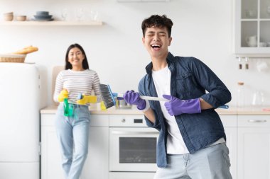 Mutfağı temizlerken rock yıldızı taklidi yapan komik Asyalı adam.