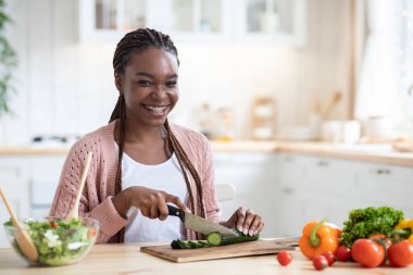 Sağlıklı yemek. Neşeli Afro-Amerikan Kadın Evde Taze Sebze Pişiriyor