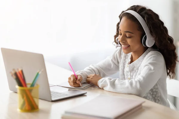 Alegre chica de la escuela que tiene lección en línea, utilizando el ordenador portátil en casa — Foto de Stock